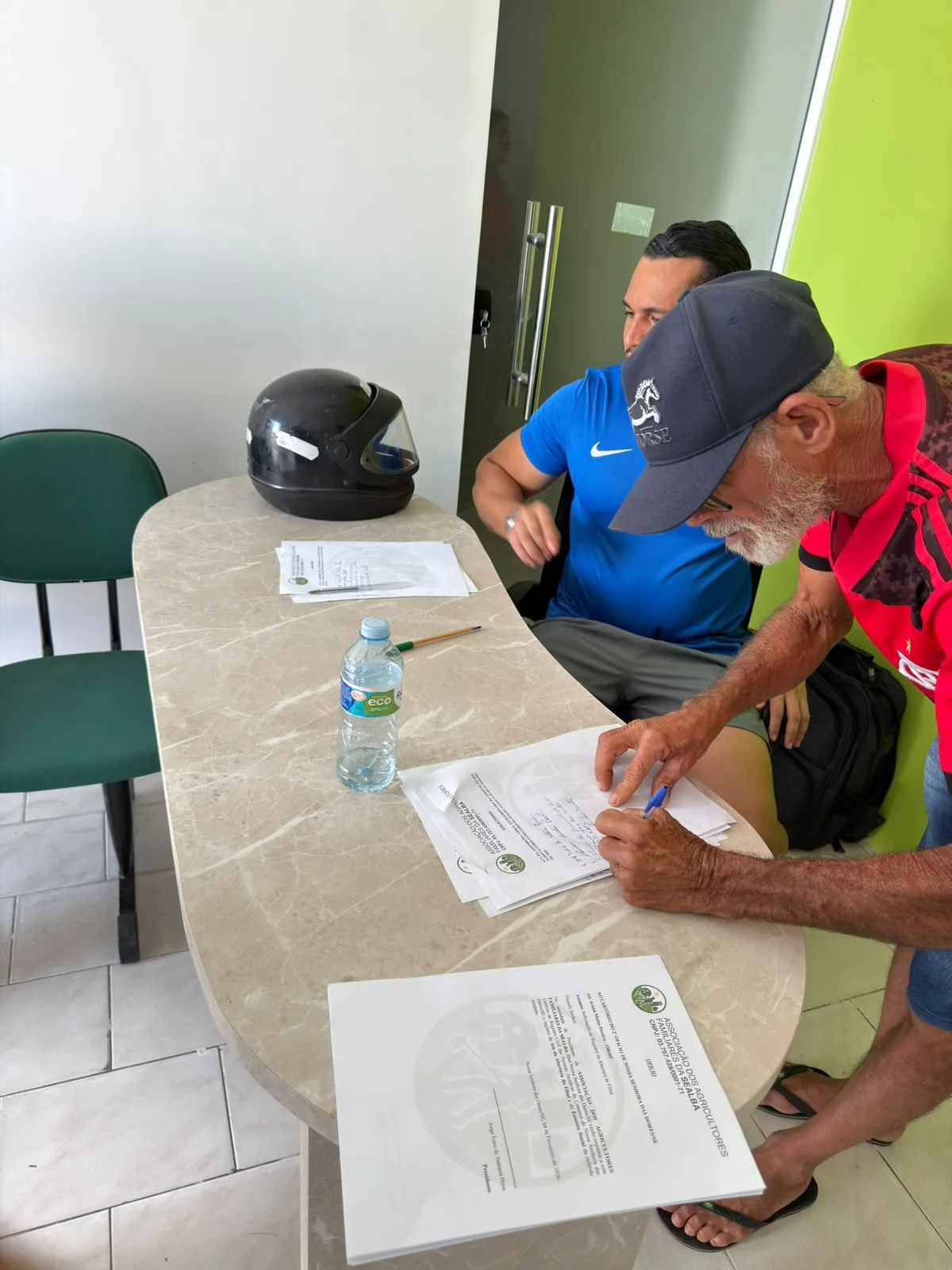 Pessoa preenchendo documento com acompanhamento em mesa de atendimento
